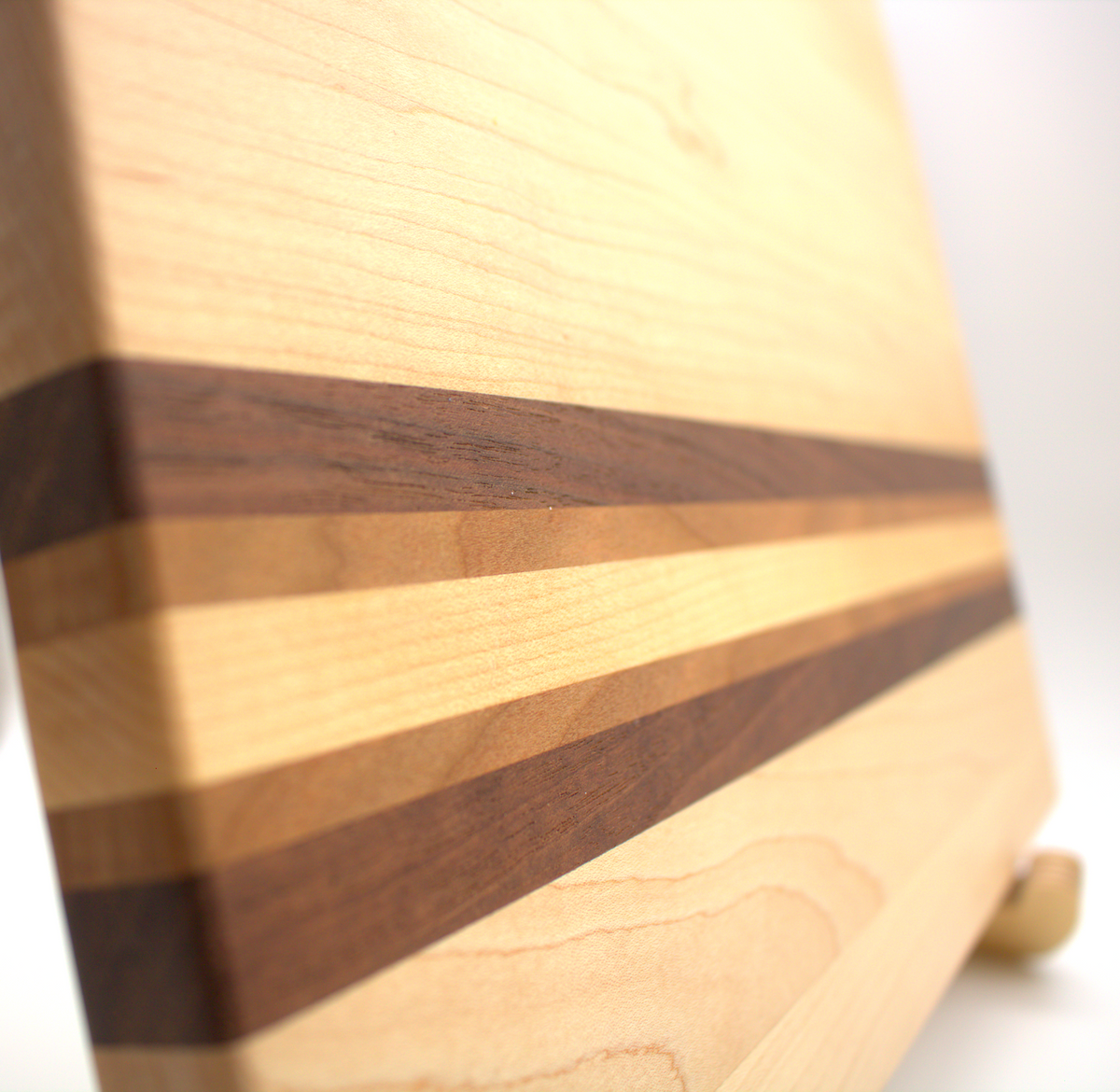 Handmade maple cutting board with walnut and cherry accent stripes, non-slip rubber feet, 16 by 12 inches